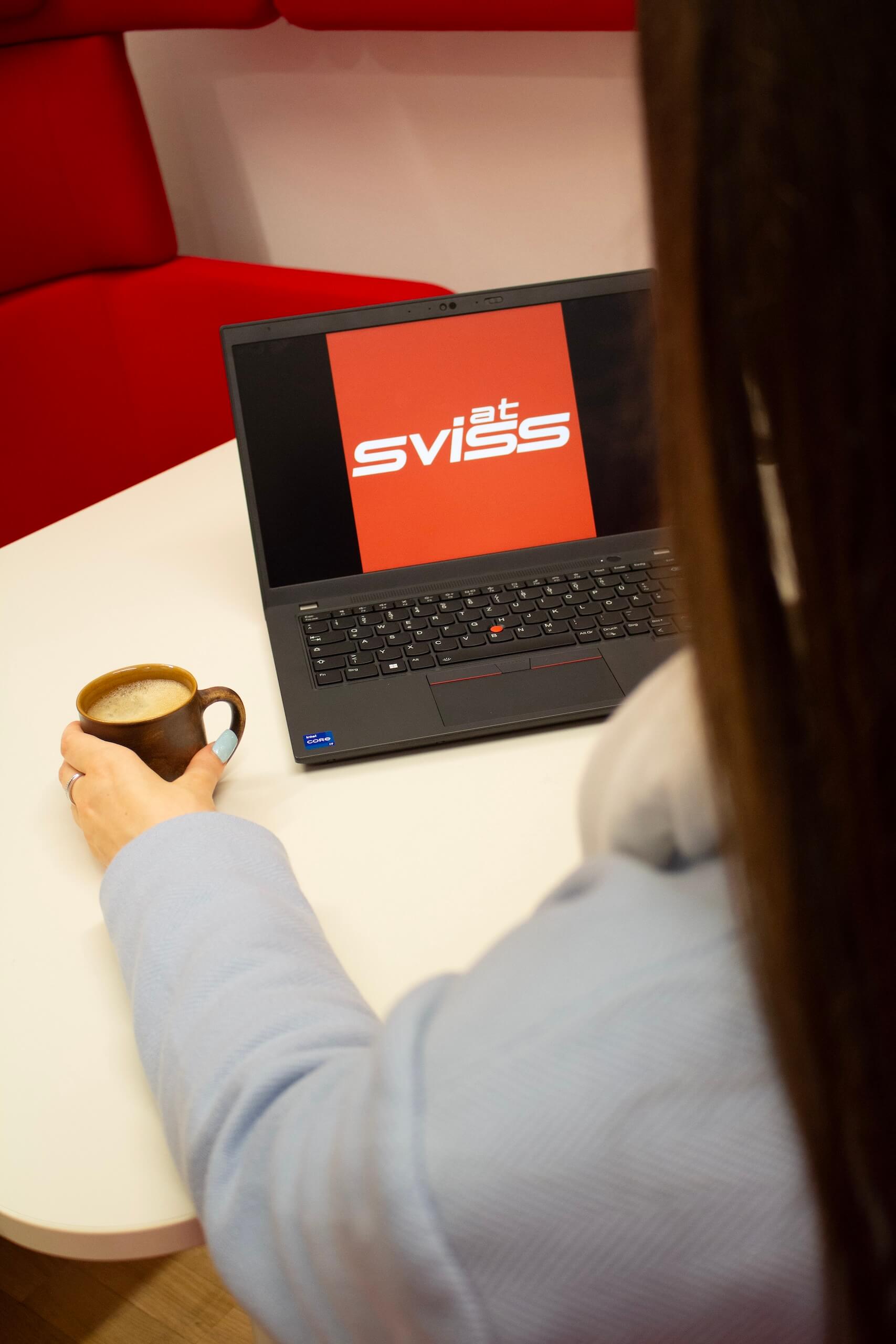 Frau sitzt vor einem Notebook mit Sviss Logo am Bildschirm