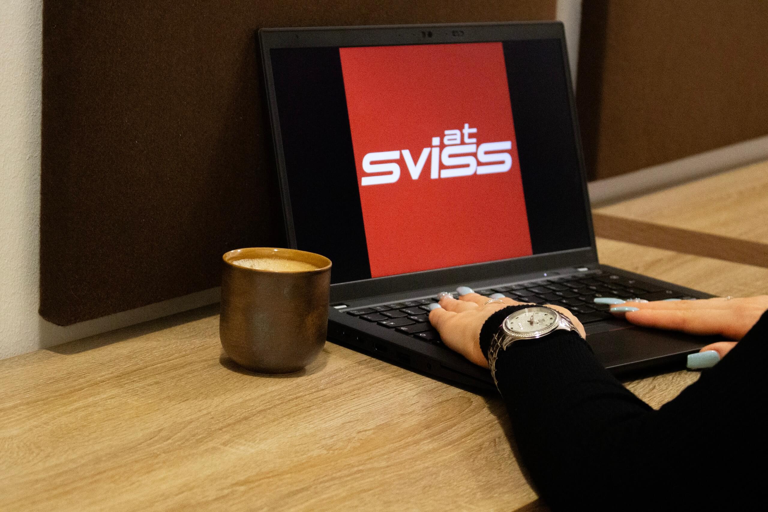 Frau sitzt vor einem Notebook mit Sviss Logo am Bildschirm